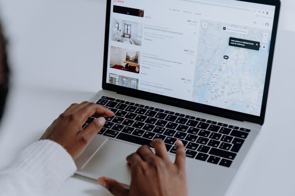 pexels-photo-5077049 Hands typing on laptop searching Airbnb for accommodation options with map view.
